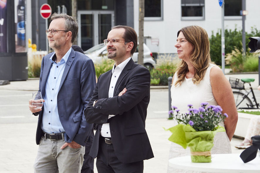 Zwei Männer und eine Frau stehen