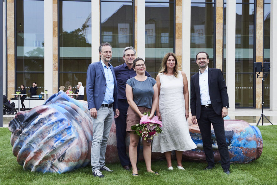 Zwei Frauen und drei Männer lassen sich vor der Skulptur fotografieren